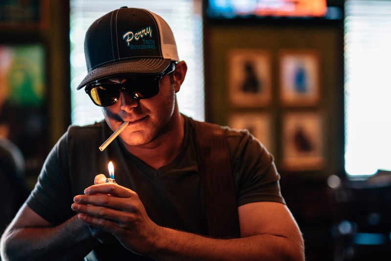 Lighter flame glowing on a capped, sunglassed face