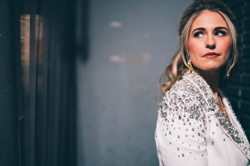 Upward glance, jeweled white jacket against moody blue