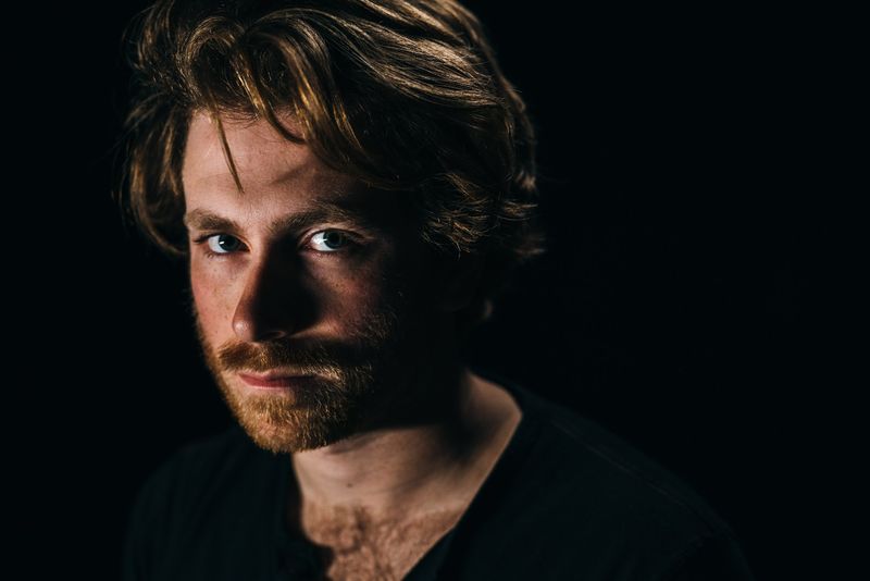 Side-lit red beard and hard stare on black