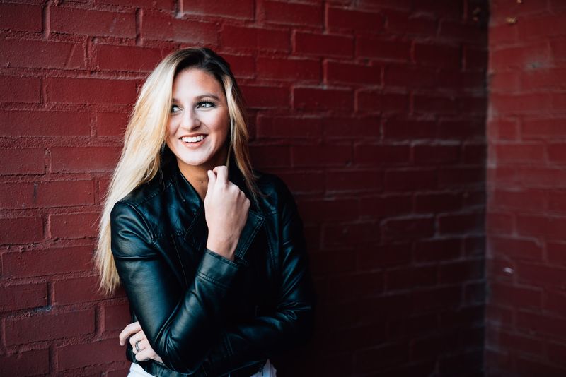 The same wall, a wide smile and a glance off frame, the red brick dark and rich
