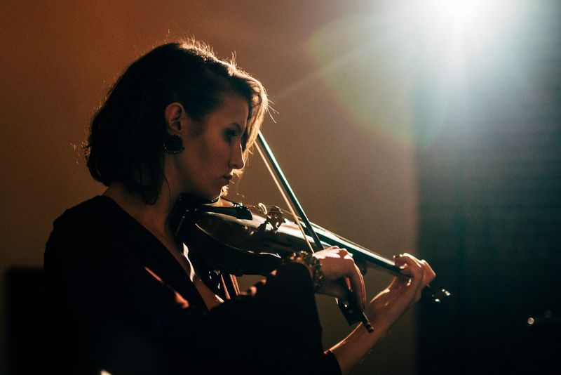 Violinist bowed into warm side light and lens flare
