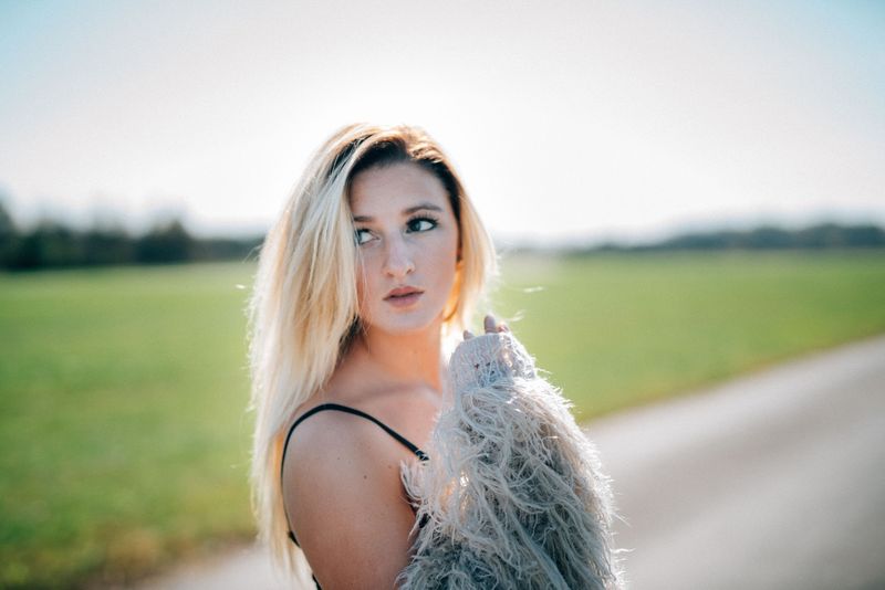 A backlit close portrait, eyes up and aside, hair glowing, the fur coat at her shoulder
