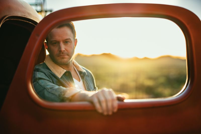 Framed in a red truck window, desert sunset glowing behind