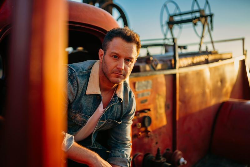 Golden-hour gaze from a weathered red truck, reels behind