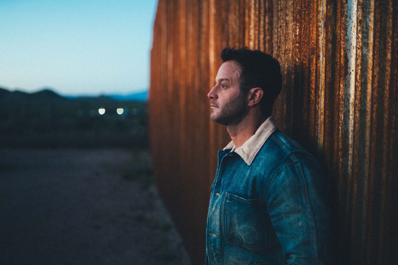 Profile against rusted corrugated wall, blue dusk desert beyond