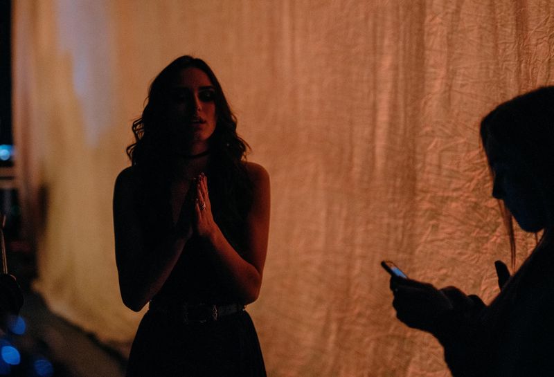 Hands pressed together before the show, silhouette scrolling a phone