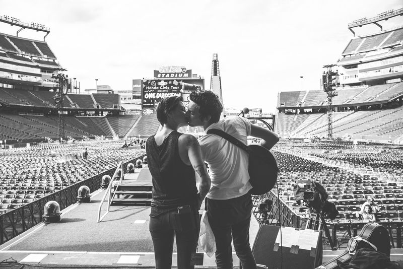 A kiss on the empty stadium runway, seats stretching away