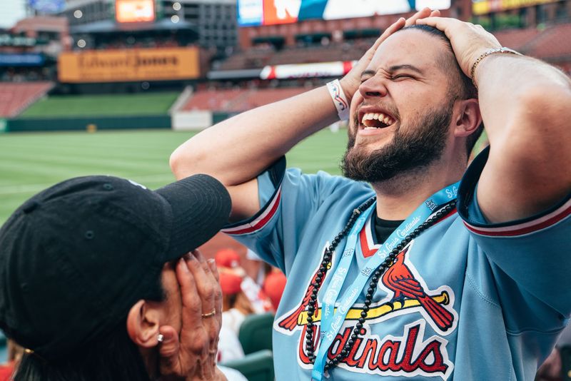 Fan clutches head in disbelief, stadium behind, huge laugh