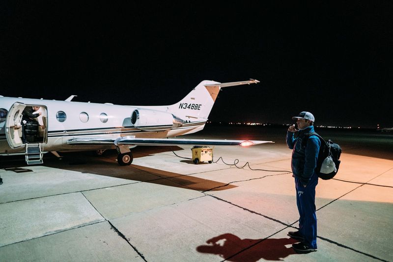 On the phone beside a private jet, hard light, long shadow