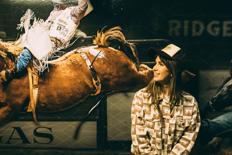 Bucking bronc overhead, a smiling woman in western print below