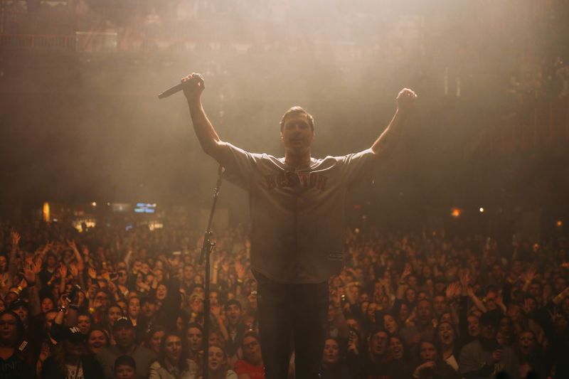 Arms flung wide over a vast crowd in warm haze