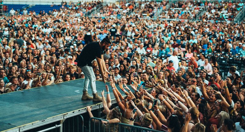 Leaning off the stage into a sea of reaching hands