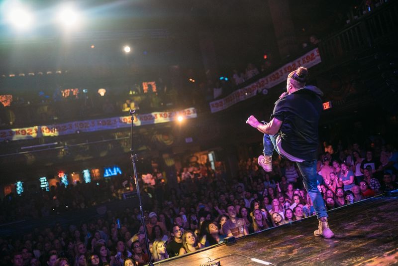 Mid-air leap with mic over a pink-lit crowd