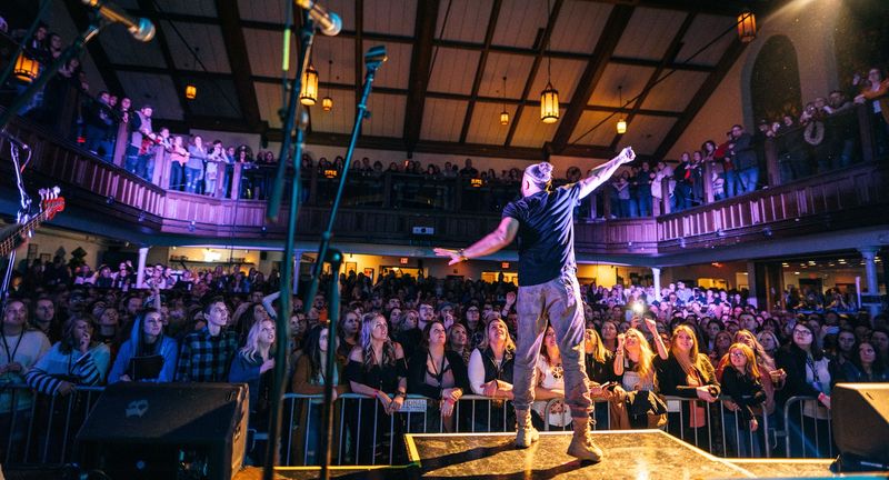 Arms out to a packed balcony from behind the stage