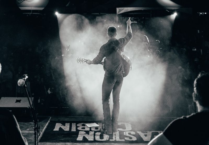 Arm raised into backlit haze, his name on the floor