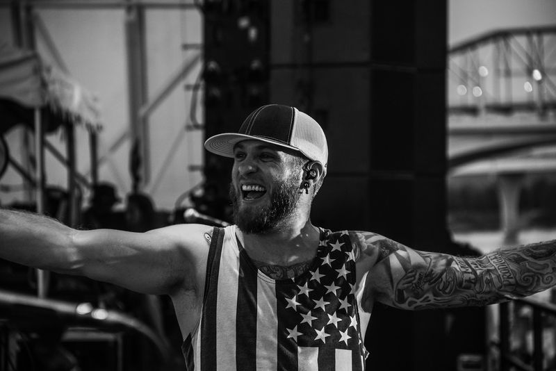 Arms flung wide, huge grin, flag tank, bridge behind
