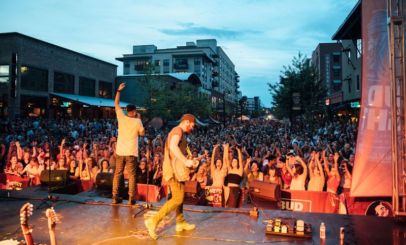 Street block party crowd arms up under blue-hour sky
