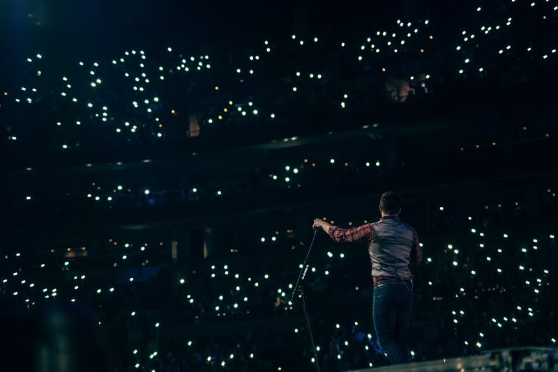 Arm out over a dark arena full of phone lights
