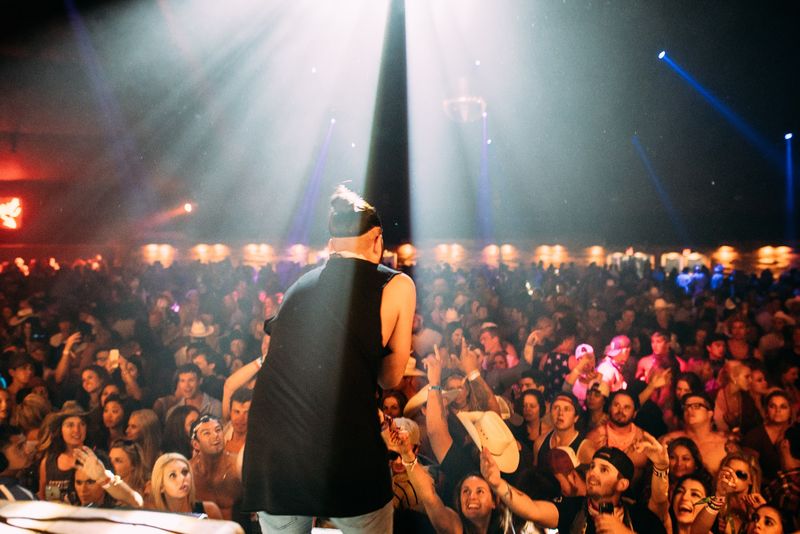 Light beam over singer's back, sea of reaching hands