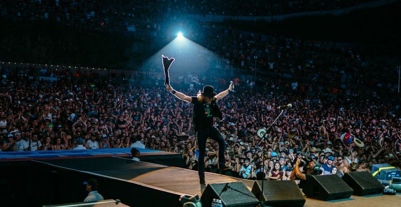 Raised arm at stage edge over a sea of crowd