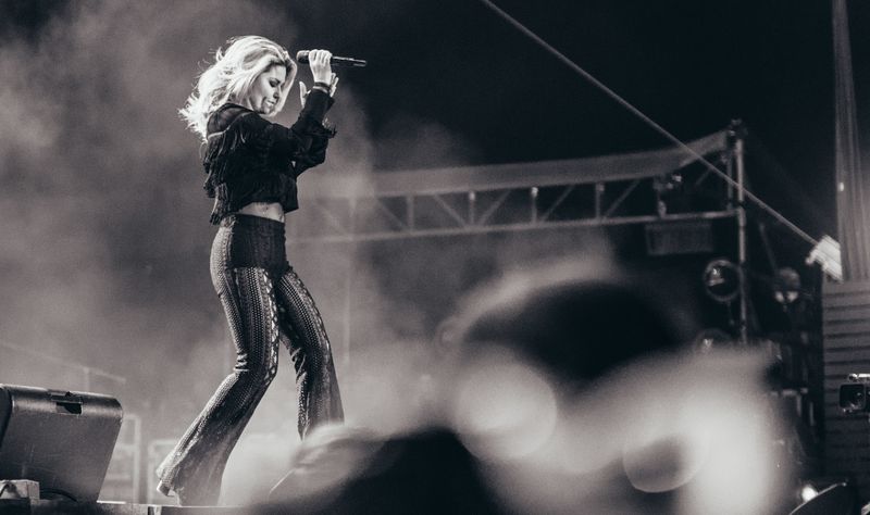 Hair flying mid-stride on a smoky festival stage, black and white